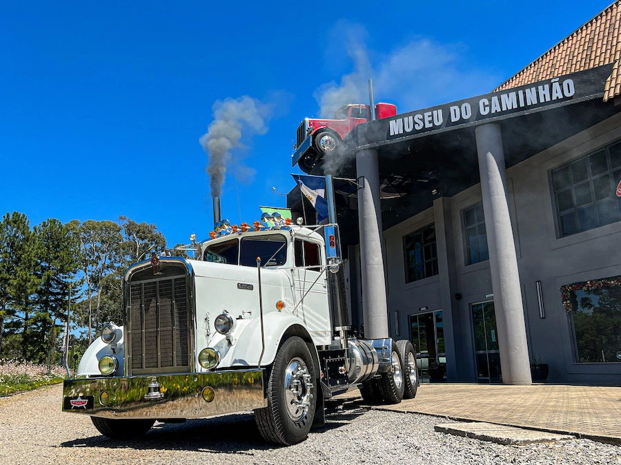 Caminhão clássico americano em frente ao Museu do Caminhão, em Canela, com fachada temática ao fundo e detalhes que remetem aos veículos das décadas de 1950 e 1960, exposto no parque American Old Trucks.