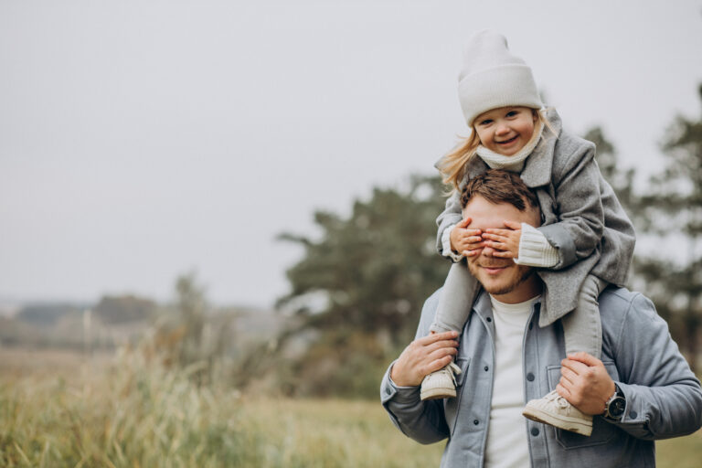 Pai carrega a filha nos ombros em um dia frio e acolhedor, com sorrisos e brincadeiras ao ar livre ,cena que traduz o espírito do Dia dos Pais em Gramado, repleto de afeto, natureza e momentos especiais em família.