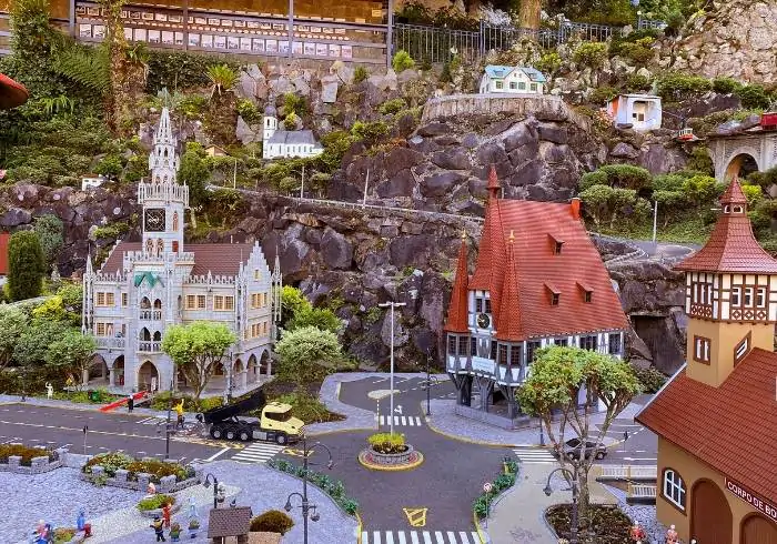 Cenário detalhado com réplicas em miniatura de construções europeias no parque Mini Mundo, um dos mais famosos parques em Gramado e Canela, com ruas, árvores e montanhas em escala reduzida.