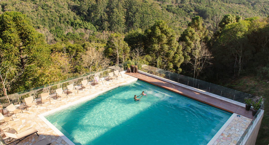 Piscina do Hotel Recanto da Serra, em Gramado, com vista para a vegetação da Serra Gaúcha, oferecendo um ambiente tranquilo e relaxante, ideal para aproveitar o turismo em Gramado.