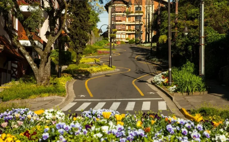 Vista da Rua Torta, um dos principais pontos turísticos e passeios gratuitos em Gramado, com flores coloridas, arquitetura europeia e paisagismo encantador.