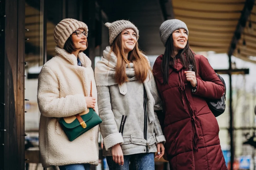 Três mulheres com roupa de inverno na rua.