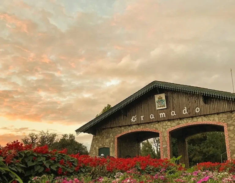 Pórtico de entrada de Gramado cercado por flores coloridas ao entardecer, um dos cartões-postais mais conhecidos da Serra Gaúcha.