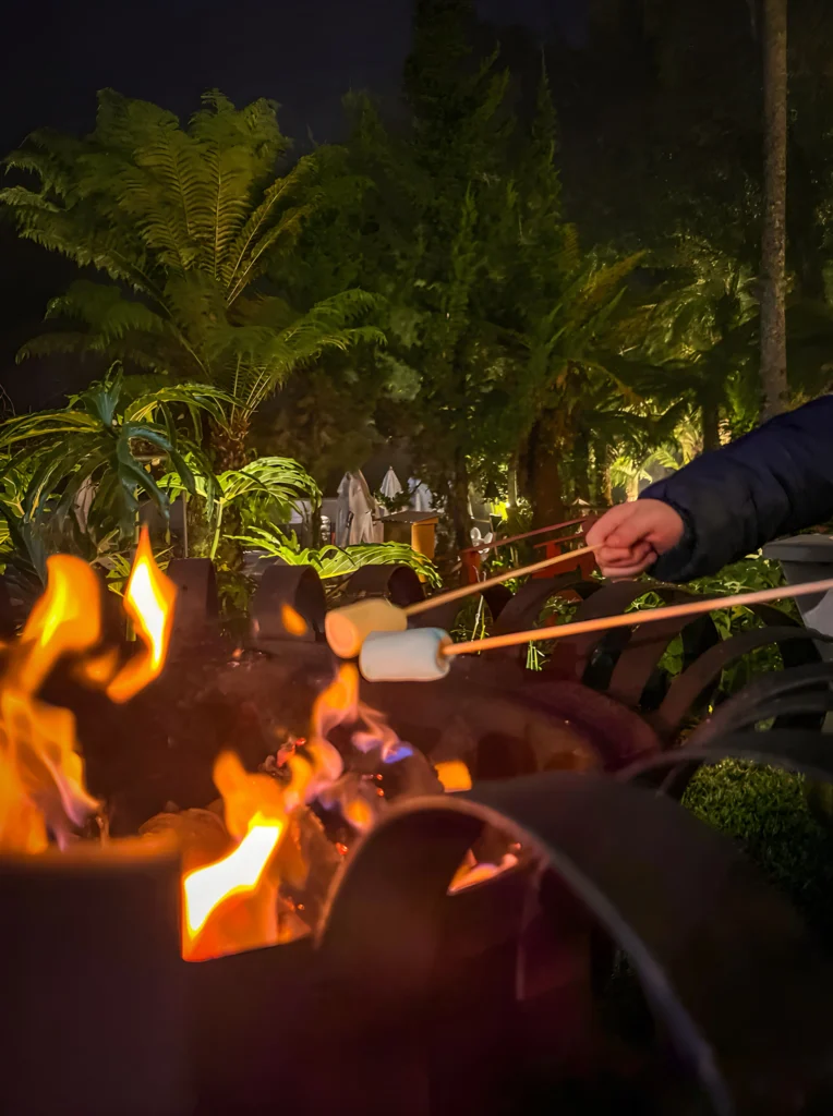 Marshmallows sendo assados na fogueira ao ar livre durante as férias de julho no hotel Recanto da Serra, em uma noite aconchegante cercada pela natureza.
