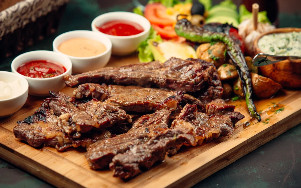 Tábua de madeira com cortes suculentos de carne assada, acompanhados de molhos e legumes grelhados, representando a gastronomia típica das churrascarias em Gramado.