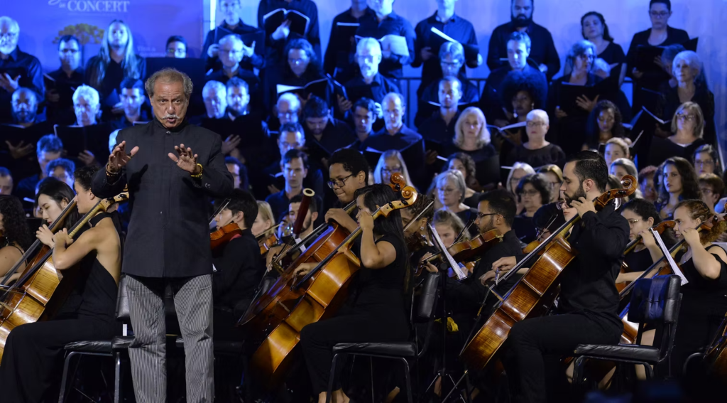 Maestro rege orquestra e coral em apresentação emocionante do Gramado in Concert, festival de música clássica na Serra Gaúcha.